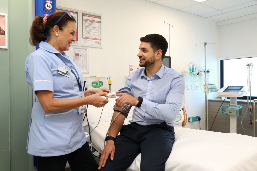 A picture of a man and a nurse on the hospital bed getting medical tests done