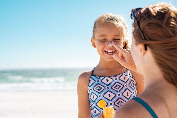 A mother applies sunscreen to her daughter's face