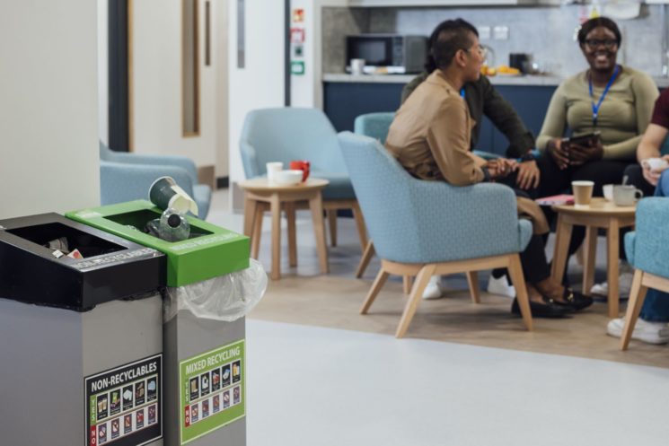 Recycling bins in office, with employees in background