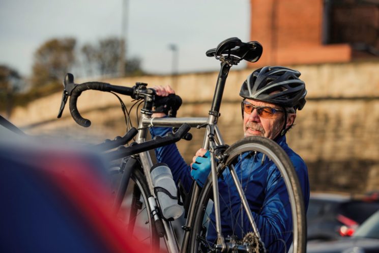 Picture of an older man taking his bicycle out from the car