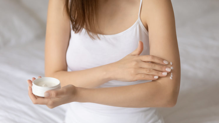 Picture of a young woman applying cream to the skin on her arm