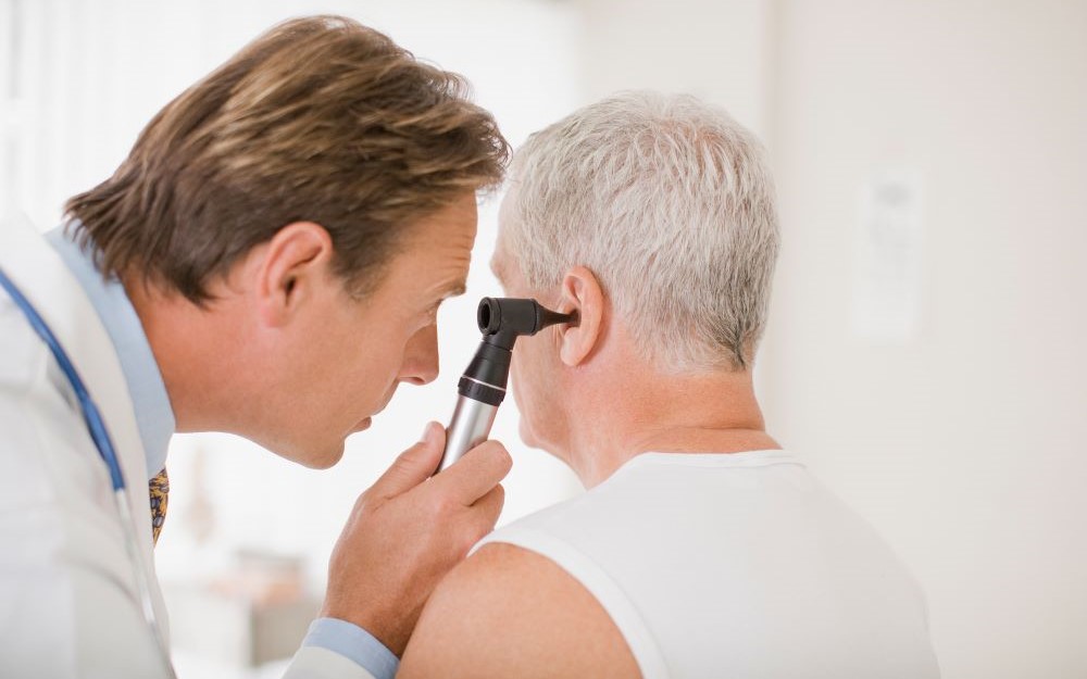 Consultant checking ear of an older man
