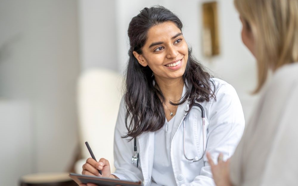 Close up picture of a consultant making notes and smiling at a patient